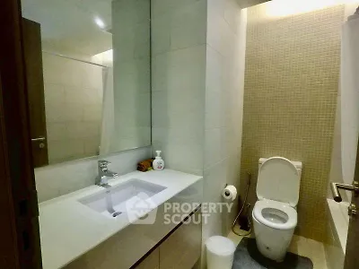 Modern bathroom with sleek fixtures and elegant tile design, featuring a spacious vanity and contemporary toilet.