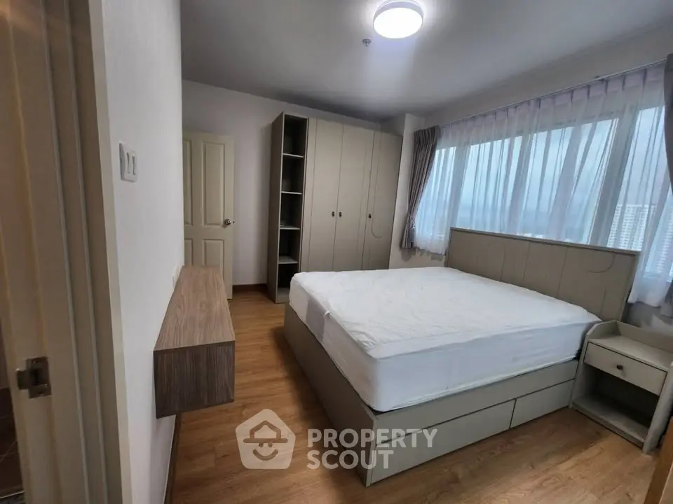 Spacious bedroom with modern furnishings and large windows for natural light.