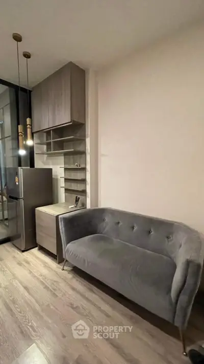 Modern apartment interior with stylish grey sofa and compact kitchen area.