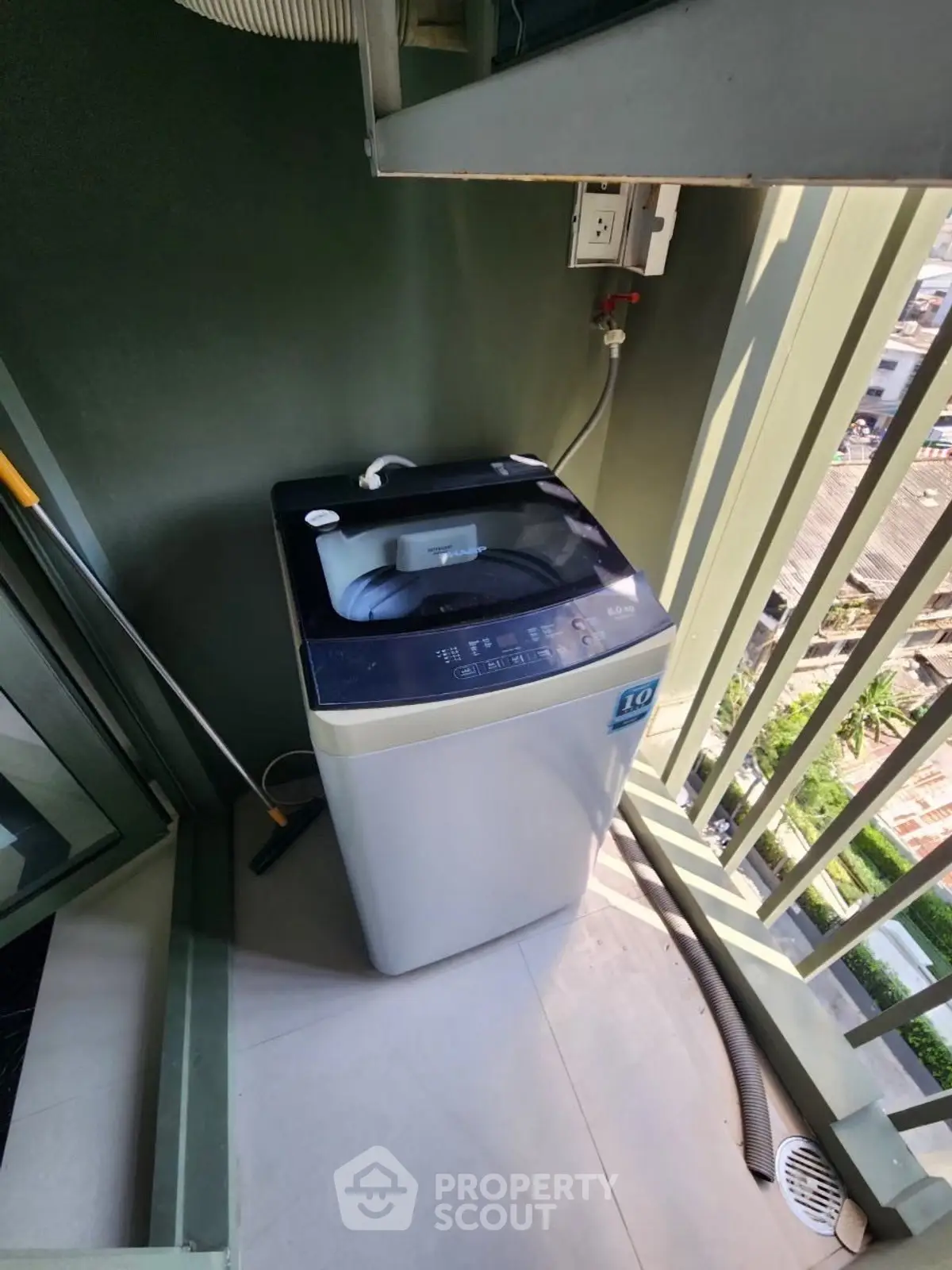 Compact balcony with washing machine and city view, ideal for urban living convenience.