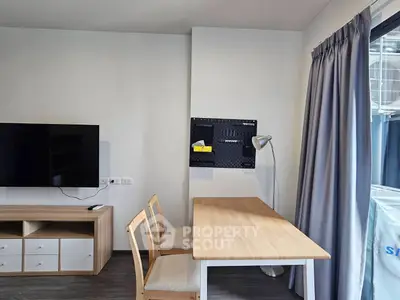 Modern living room with TV, wooden table, and chairs, featuring a sleek design and natural light.