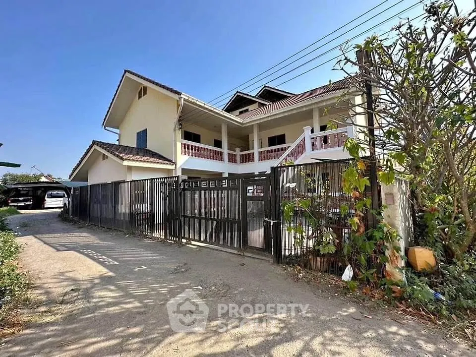 Spacious two-story house with gated entrance and lush greenery