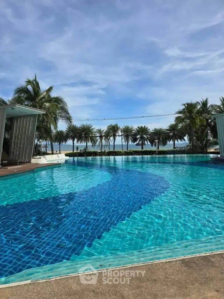 Luxurious beachfront pool with palm trees and ocean view, perfect for relaxation and leisure.
