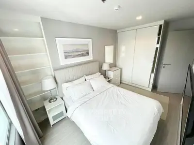 Modern bedroom with white decor, built-in wardrobe, and natural light.