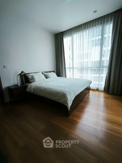 Modern bedroom with large window and wooden flooring in a stylish apartment