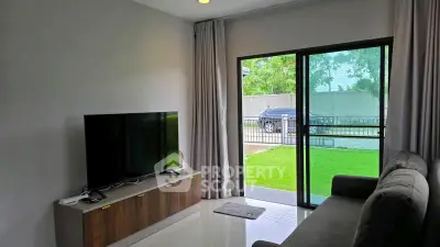Modern living room with large TV and sliding glass doors to lush garden