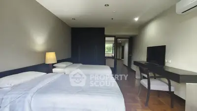 Spacious bedroom with twin beds, modern decor, and natural light, perfect for comfort and relaxation.