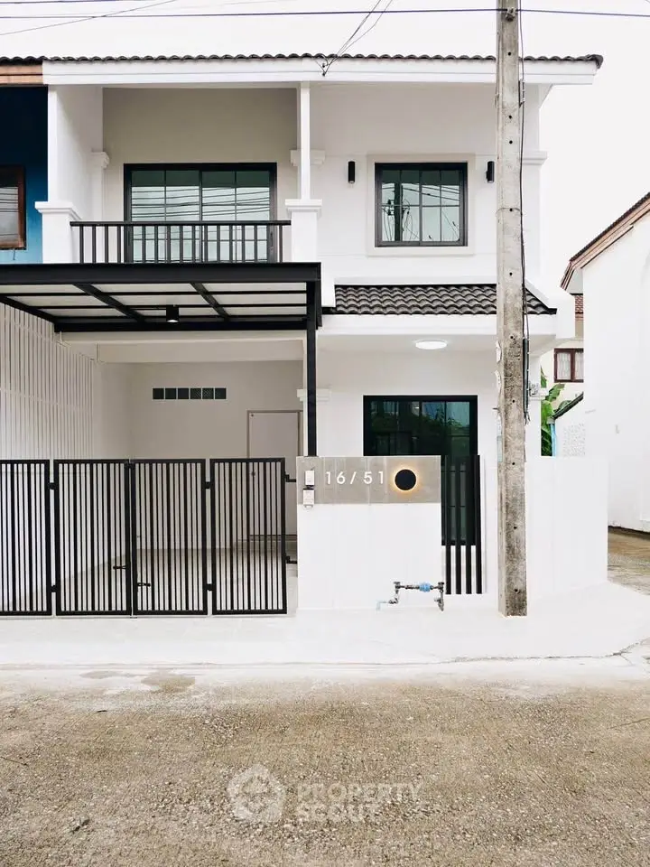 Modern two-story house with sleek design and gated entrance in a suburban neighborhood.