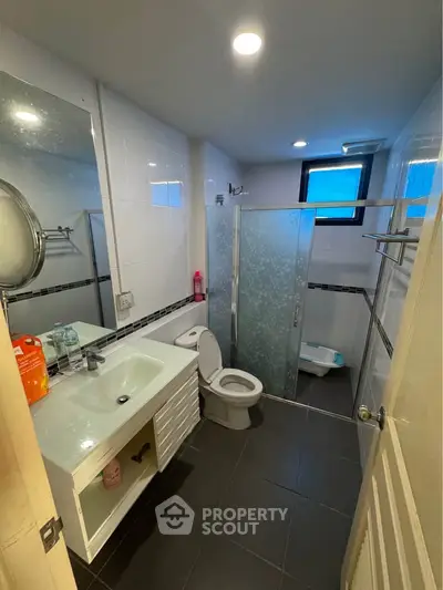 Modern bathroom with glass shower and sleek fixtures in contemporary apartment.