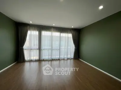 Spacious empty room with elegant curtains and wooden flooring, perfect for customization.