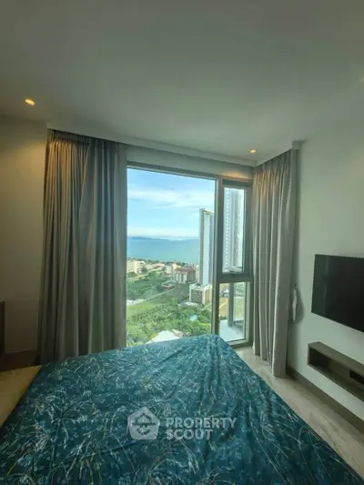 Luxurious bedroom with stunning city and sea view from large window, modern decor and TV.