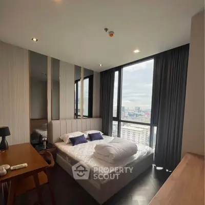 Modern bedroom with large windows offering stunning city views, featuring a cozy bed and elegant decor.
