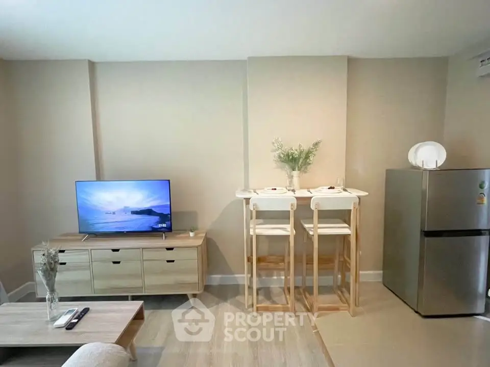 Modern living room with TV, stylish furniture, and compact dining area.