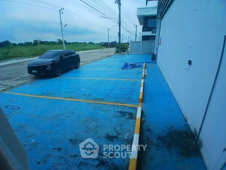 Spacious parking area with a single car, adjacent to a modern building, ideal for commercial use.