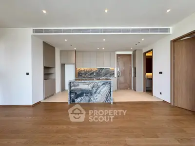 Luxurious open-plan kitchen with marble island and wooden flooring in modern apartment.