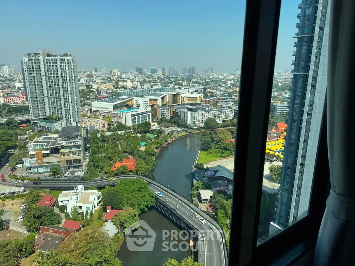 Stunning cityscape view from high-rise apartment window overlooking river and urban skyline.