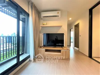 Modern living room with balcony view and sleek wooden TV stand.