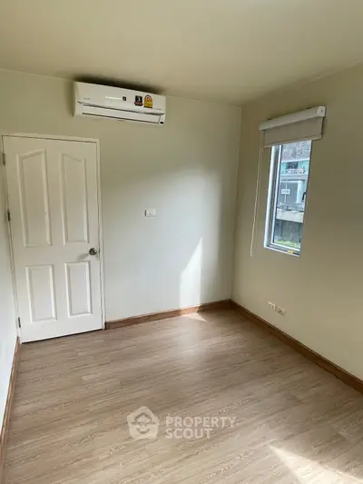 Spacious empty room with air conditioning and wooden flooring, perfect for customization.