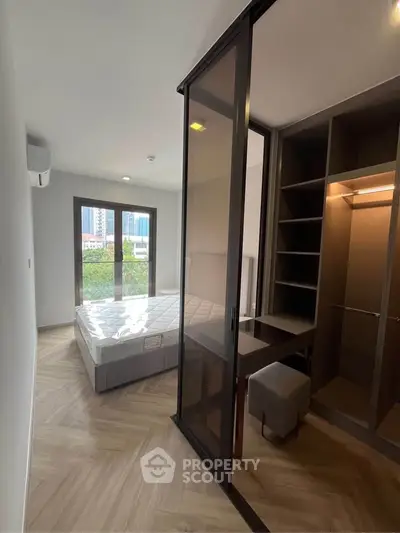 Modern bedroom with large windows and built-in closet in urban apartment