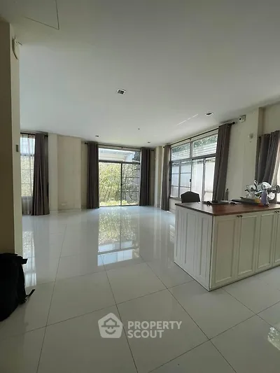 Spacious modern living room with large windows and sleek tile flooring