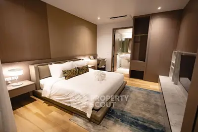 Luxurious modern bedroom with elegant decor and ensuite bathroom, featuring cozy lighting and stylish furnishings.