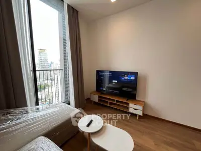 Modern living room with city view, featuring a sleek TV setup and cozy seating area.