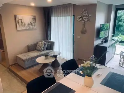 Modern living room with stylish decor and natural light, featuring a cozy seating area and a view of greenery.