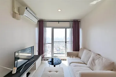 Modern living room with city view, featuring a cozy sofa and sleek TV setup.