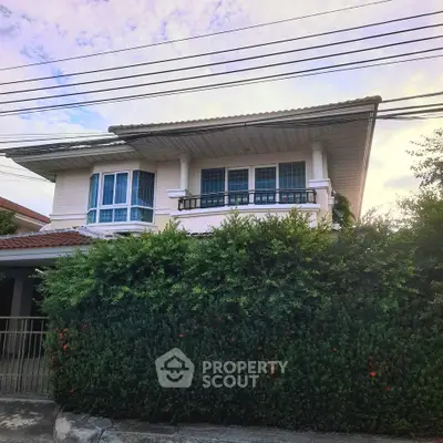 Charming two-story house with lush greenery and a classic tiled roof, perfect for family living.