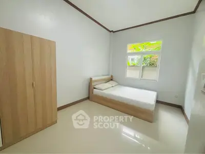 Spacious minimalist bedroom with natural light and modern wooden furniture.