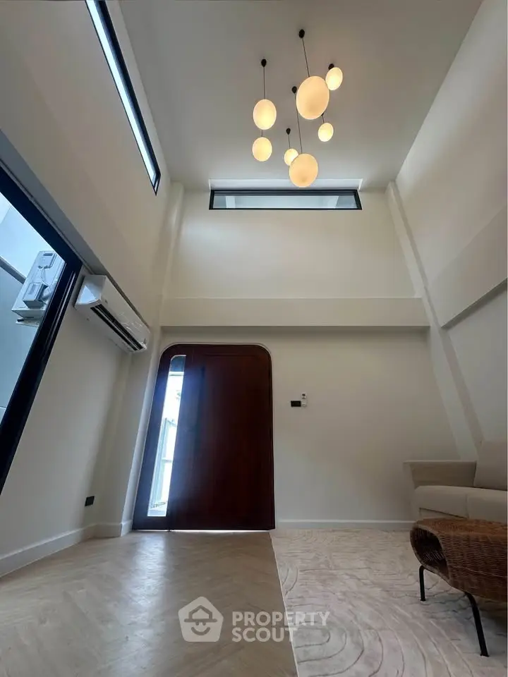 Spacious modern living room with high ceilings and elegant lighting, featuring a cozy sofa and stylish flooring.
