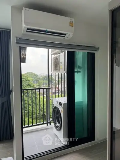 Modern apartment with balcony, air conditioning, and washing machine, offering a serene view of greenery.