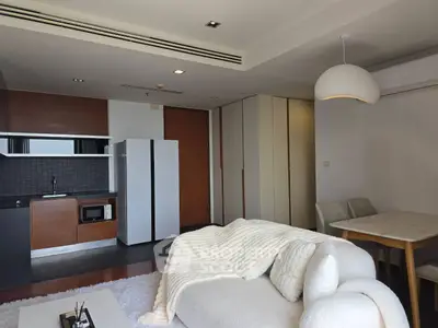 Modern living room with open kitchen and cozy dining area in stylish apartment.