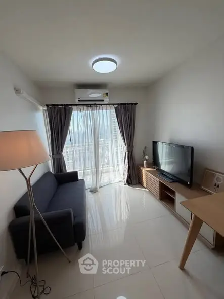 Bright living room with modern furniture and large window offering city view.