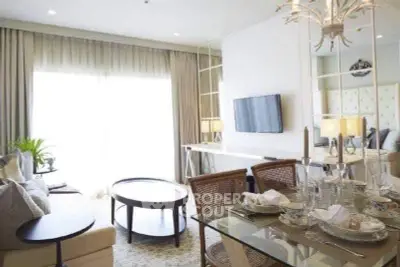 Elegant living room with modern decor and dining area, featuring a stylish chandelier and natural light.