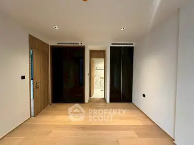 Spacious modern bedroom with wooden flooring and sleek built-in wardrobes.