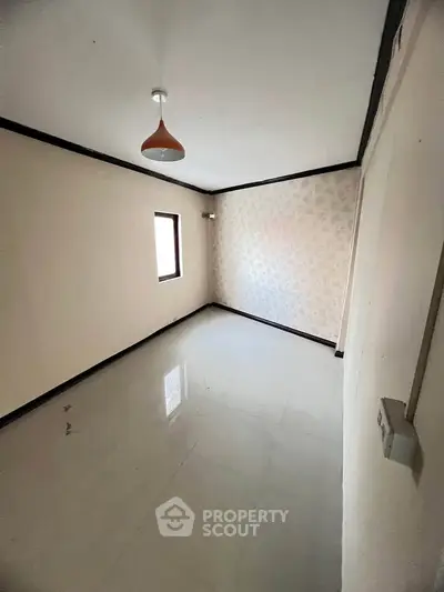 Spacious empty room with glossy tiled floor and modern light fixture, perfect for customization.