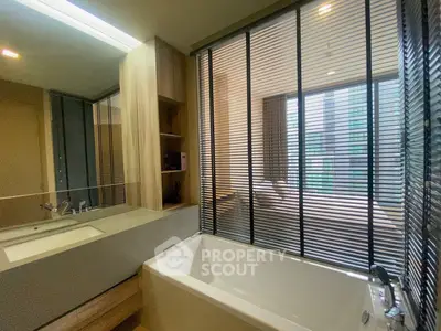 Modern bathroom with sleek design and large bathtub, featuring stylish blinds and wood accents.