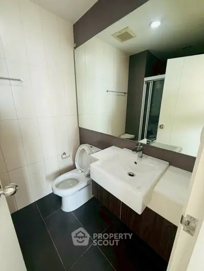 Modern bathroom with sleek fixtures and large mirror in a contemporary apartment.