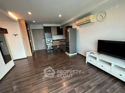 Spacious modern living room with open kitchen, wooden flooring, and stylish furniture.