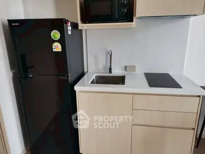 Modern compact kitchen with sleek black fridge and built-in appliances