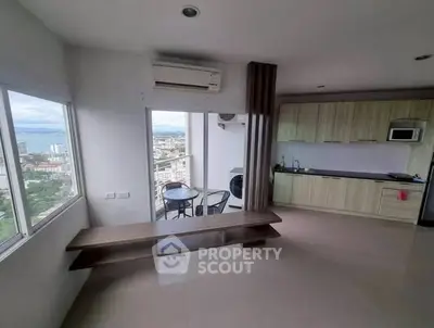Modern apartment with open kitchen and stunning city view from balcony.