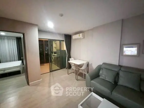 Modern apartment living room with balcony and bedroom view, featuring sleek furniture and air conditioning.