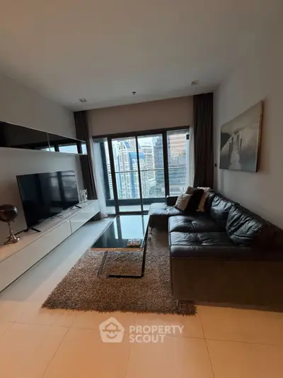 Modern living room with large TV, leather sofa, and city view through floor-to-ceiling windows.