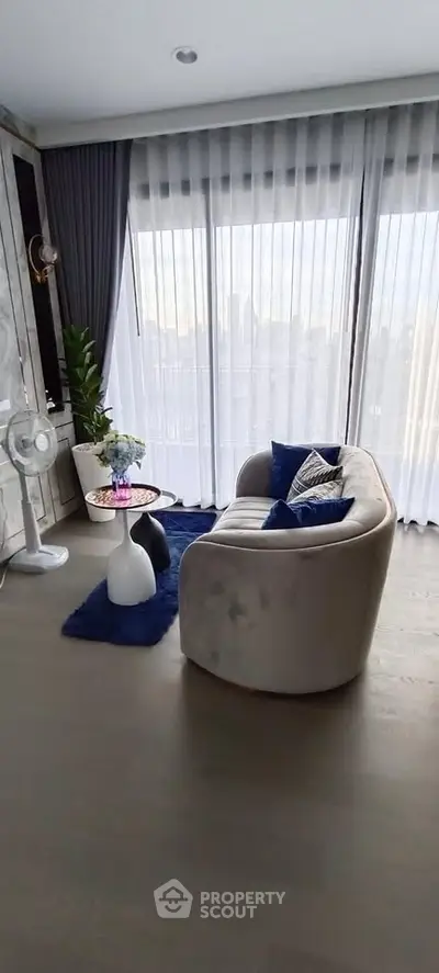 Stylish living room with modern sofa and floor-to-ceiling windows offering city views.