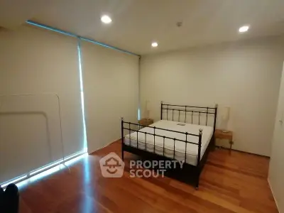 Spacious bedroom with wooden flooring and modern bed frame, ideal for comfort and relaxation.
