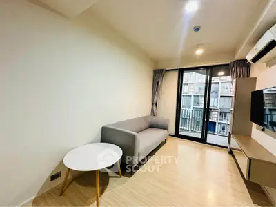 Modern living room with balcony view, featuring sleek furniture and natural light.