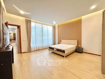 Spacious modern bedroom with large windows and elegant wooden flooring.