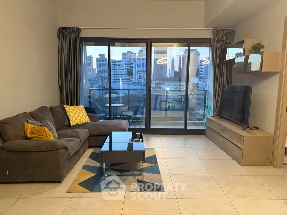 Modern living room with city view, stylish furniture, and large windows leading to a balcony.