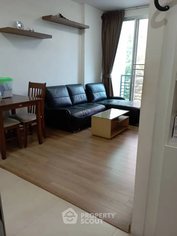 Cozy living room with modern furniture and natural light from balcony.